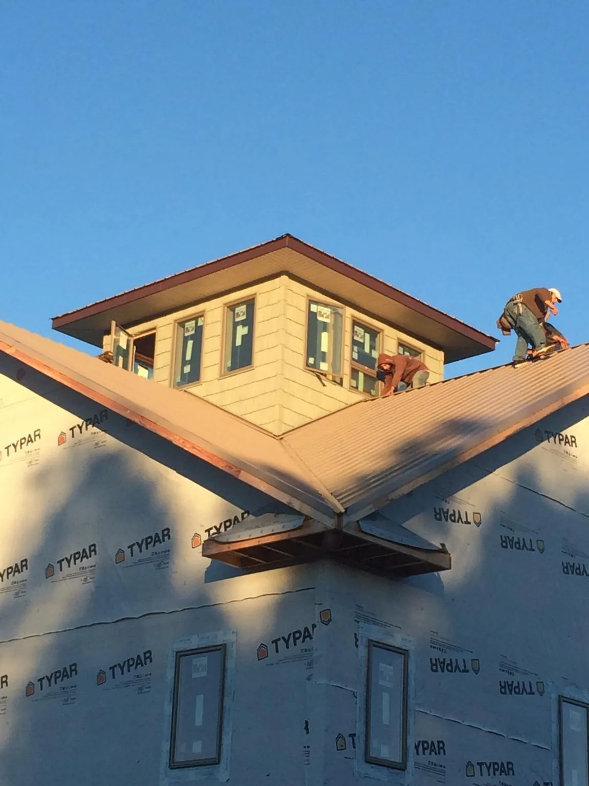 Roofers working around a rooftop cupola on a new metal roof at sunset — Roof Waterproofing in Lakeview by Roofing Brothers